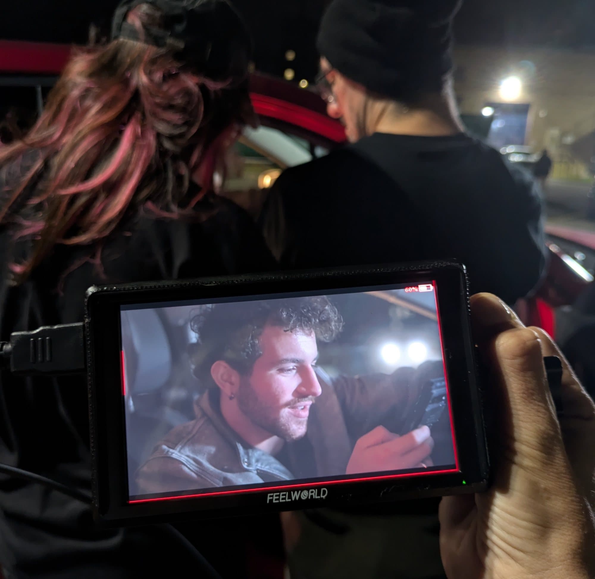 AJ DeAugustine on a camera monitor on set at night